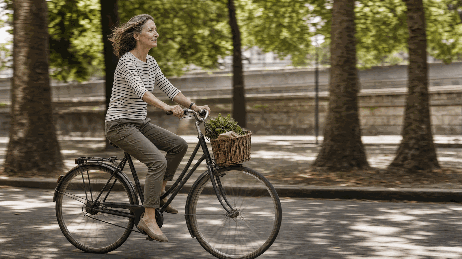 Donna in bicicletta su strada pianeggiante in città, pedalata sciolta