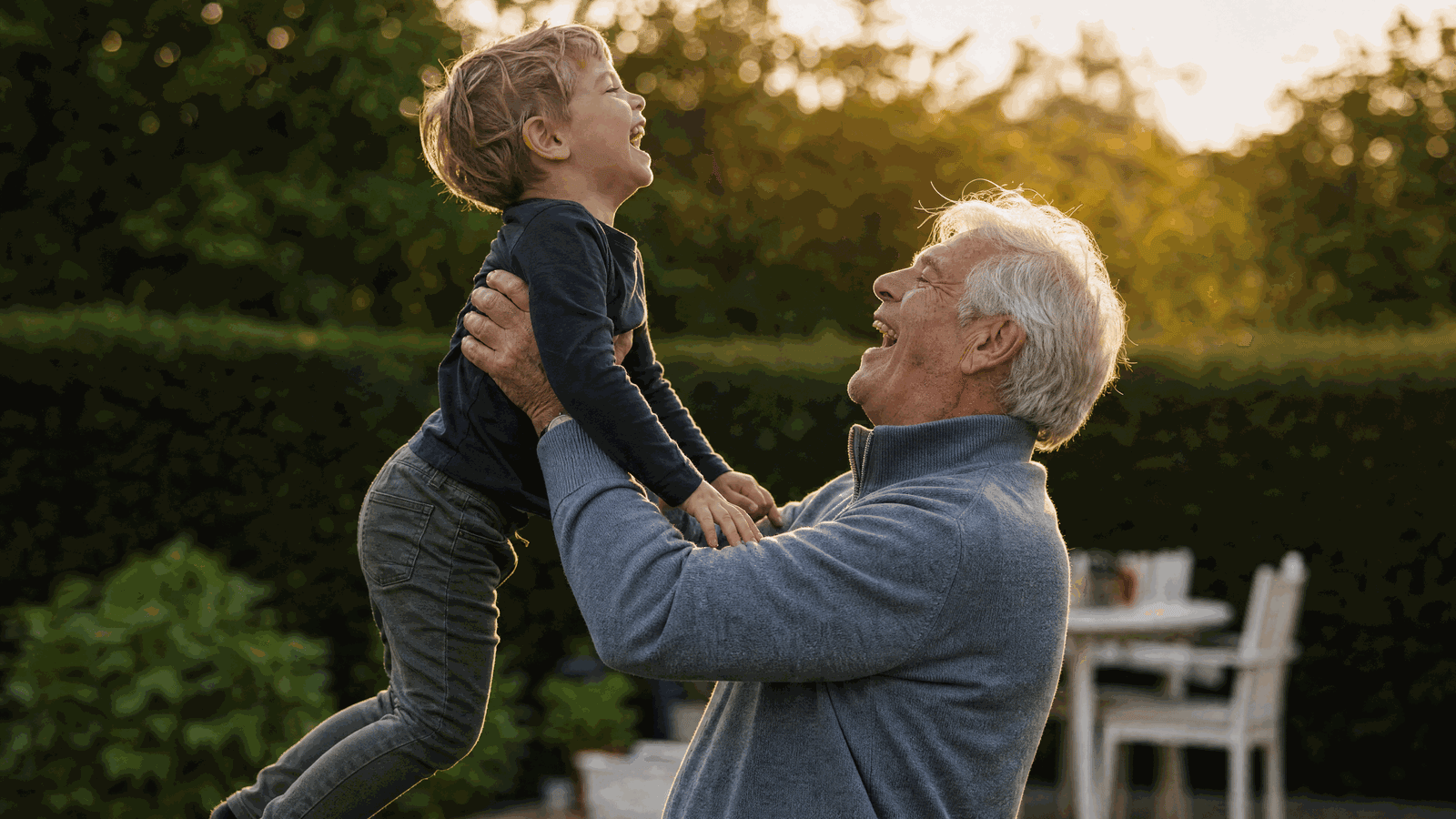 Nonno che solleva in braccio il nipote piccolo, entrambi sorridenti